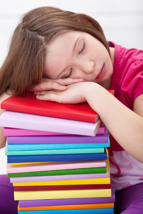 Exhausted young girl asleep on book stack
